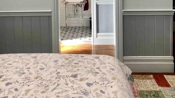 Un dormitorio con una cama, un aparador, un espejo y una puerta que da al baño.