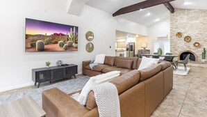A spacious living area with a large sectional sofa, a fireplace, and a kitchen in the background. - Keirland Kottage (Scottsdale)