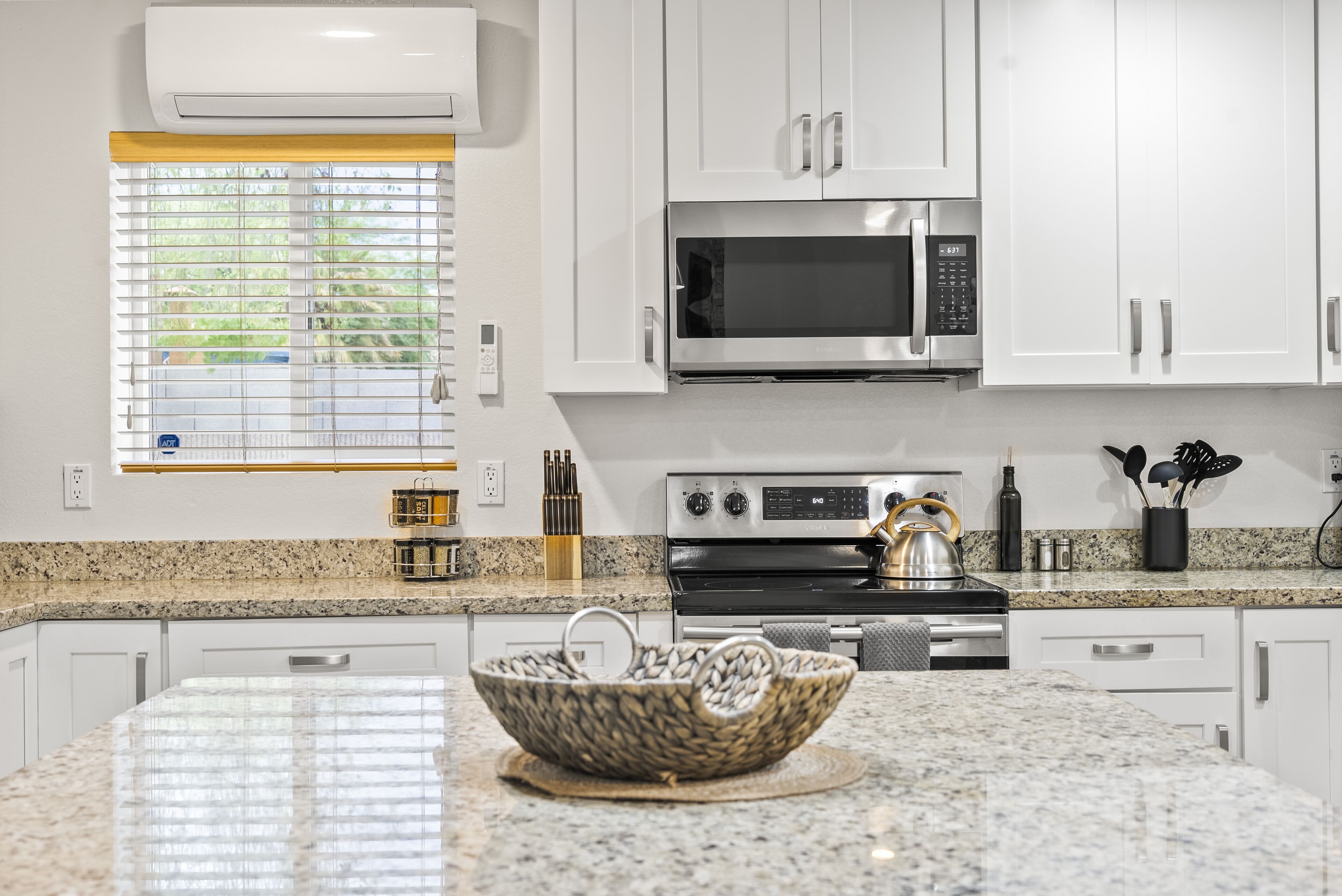 A modern kitchen with white cabinets, a stainless steel microwave, a gas stove, and a granite countertop.