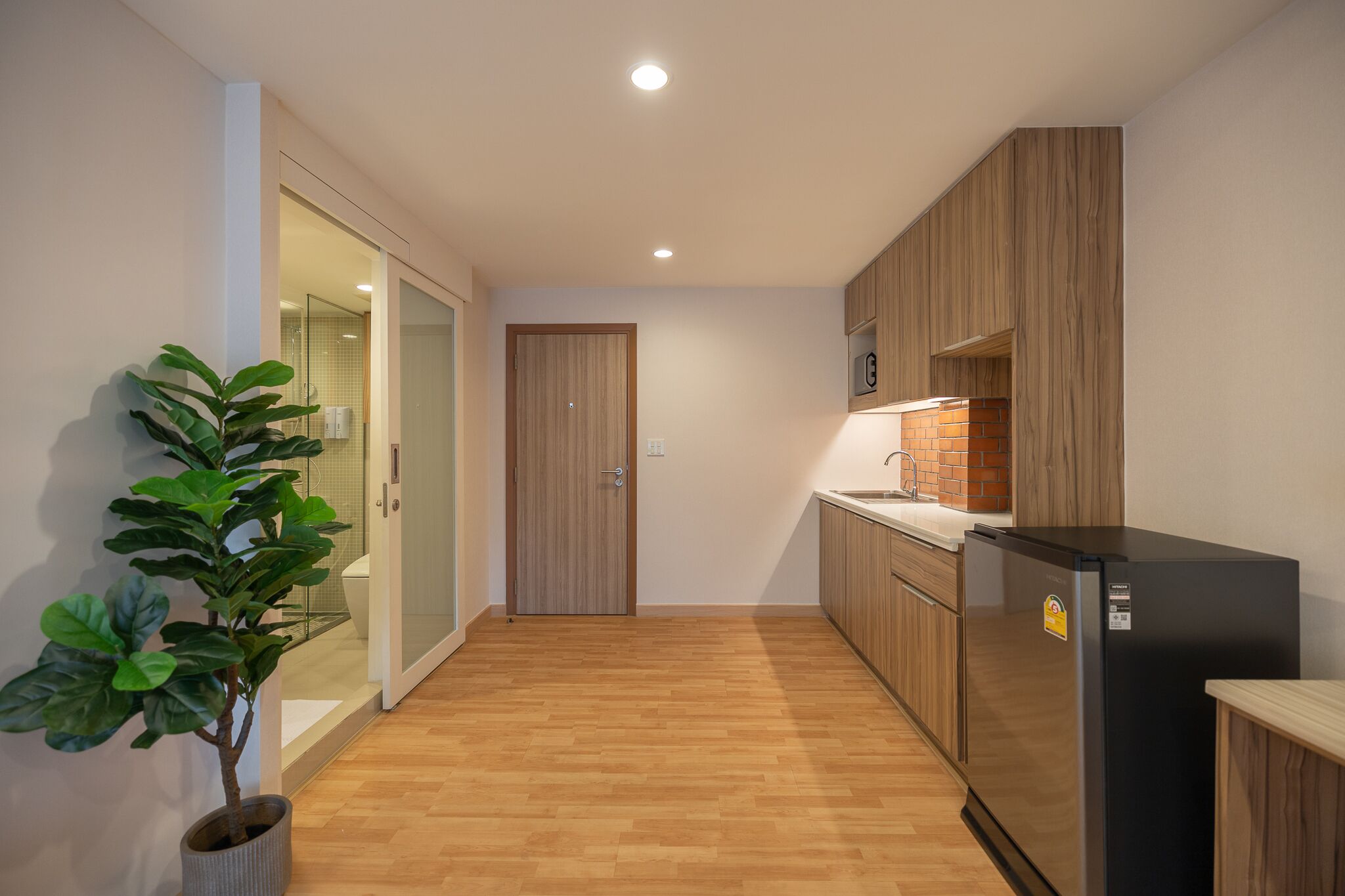 Una cocina moderna con armarios de madera, un refrigerador negro y una planta en maceta.