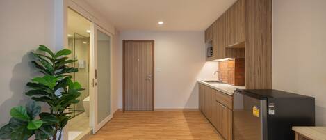 Una cocina moderna con armarios de madera, un refrigerador negro y una planta en maceta.