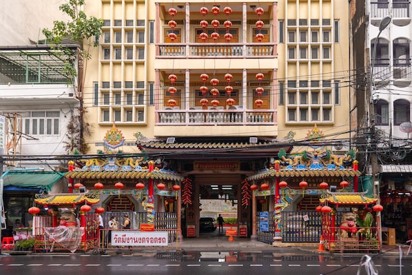 A traditional building with ornate decorations, a signboard, and a small shrine area.