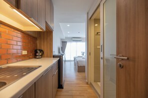 A modern kitchen with a brick backsplash, wooden cabinets, and a countertop. - EXORESIDENCE - Heart of Chinatown (Bangkok)