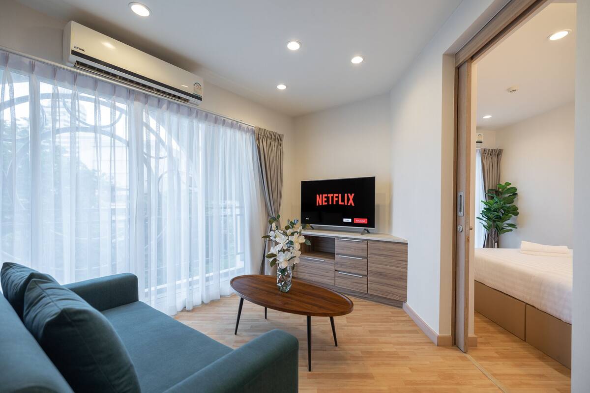 A modern living room with a sofa, a coffee table, and a TV displaying 'NETFLIX'.