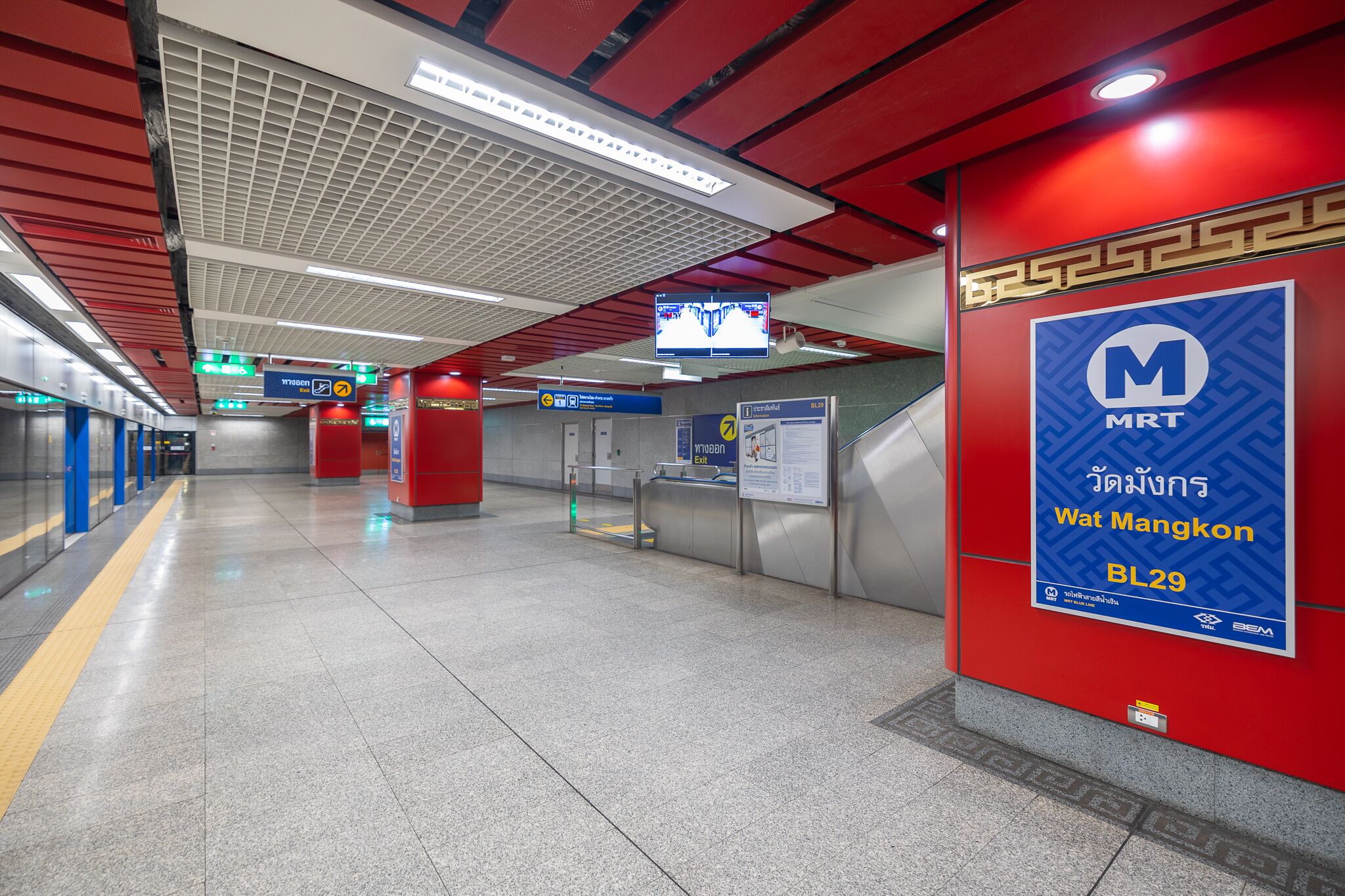 Una estación de tren moderna con señalización clara, una pantalla informativa digital y una paleta de colores rojo y azul.