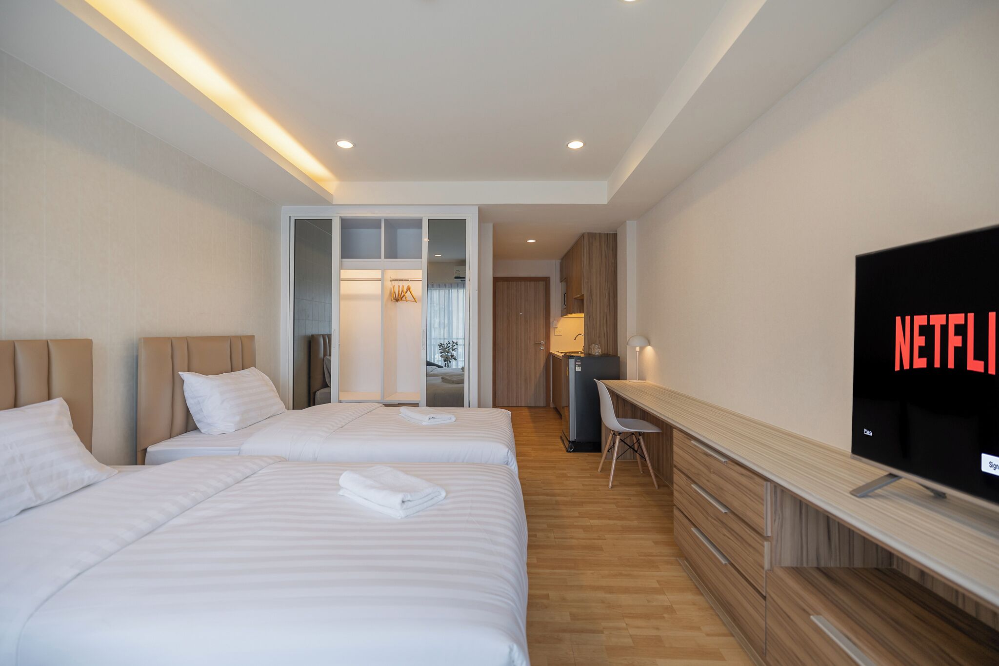 Ein Hotelzimmer mit zwei Betten, einem Schreibtisch, einem Fernseher und einer Küchenzeile.