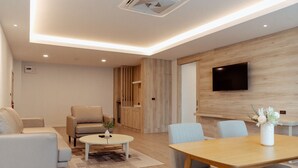 A modern living room with a sofa, armchair, coffee table, and dining table. - RUS Hotel&Convention (Ayutthaya)