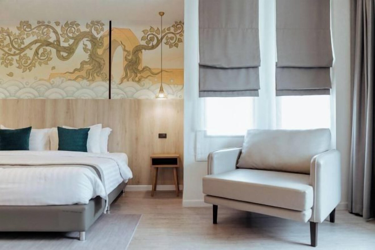 Un dormitorio moderno con una cama, una silla, una mesita de noche y un mural decorativo.