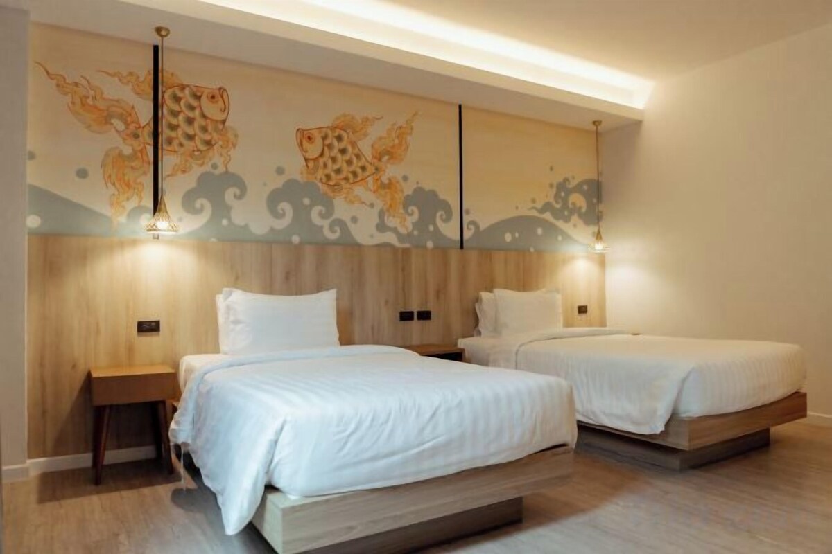 A modern bedroom with two beds, wooden headboard, and artwork on the wall.