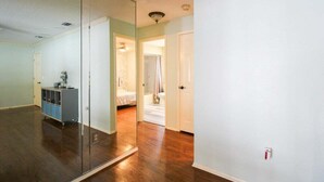 Une pièce dotée d’un grand miroir, d’un parquet en bois, d’une armoire bleue et d’une porte donnant sur une autre pièce.