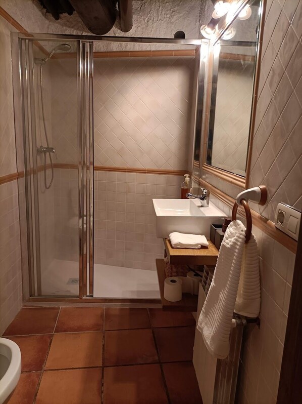 A bathroom with a glass-enclosed shower, a sink, a mirror, and a towel rack.