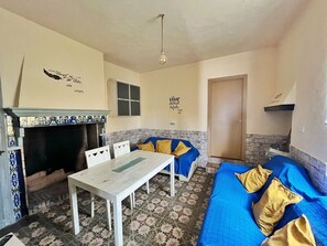 A room with a fireplace, a dining table, a sofa, and a bed.