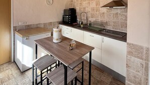 Une cuisine compacte avec des poutres en bois au plafond, une cuisinière intégrée et un pare-feu en pierre.