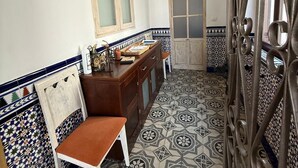 Une salle de bain avec un meuble-lavabo en bois, une chaise, un miroir et des carreaux à motifs.