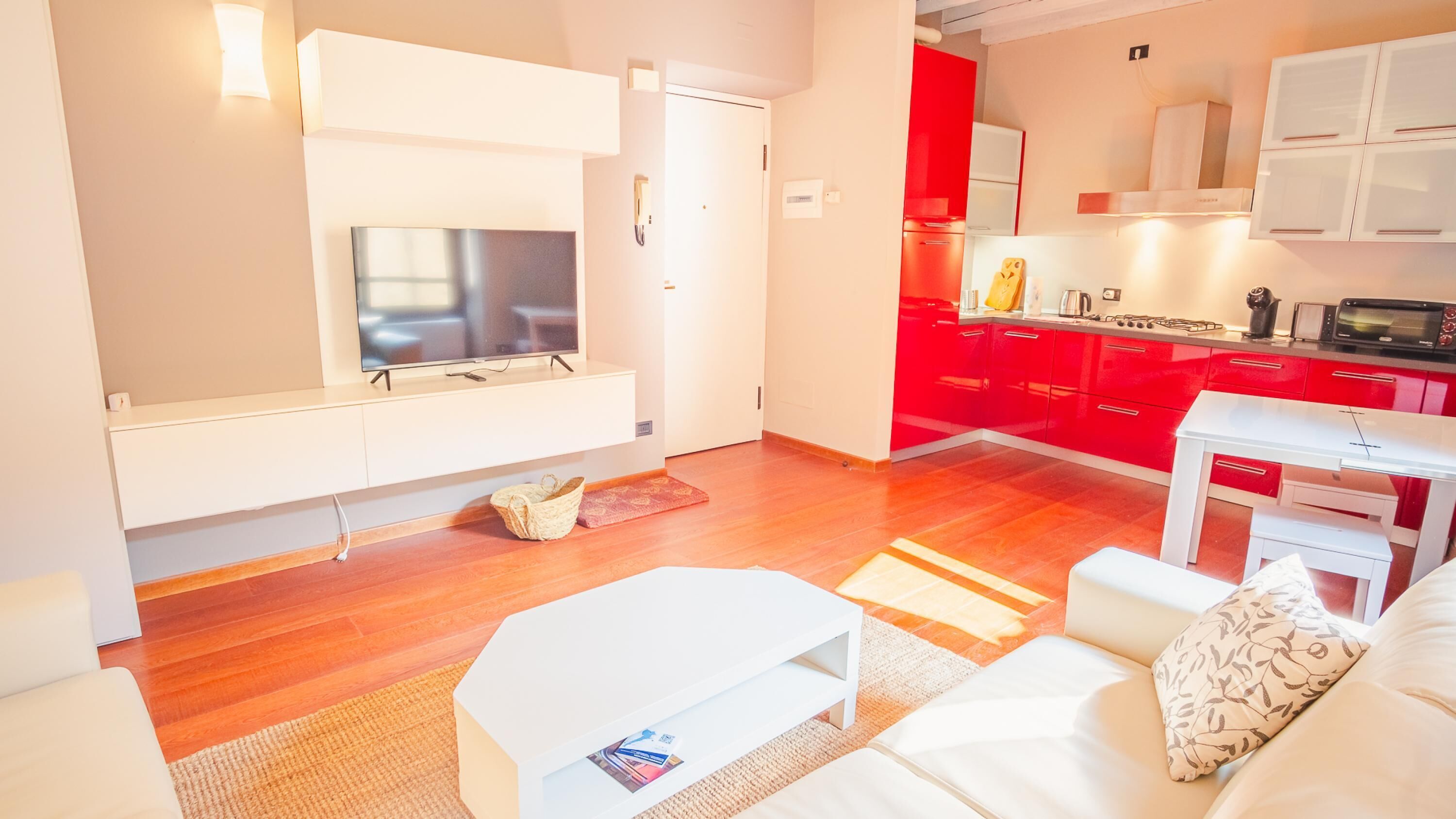 Un salon moderne avec un téléviseur à écran plat, un canapé blanc et une petite table blanche.