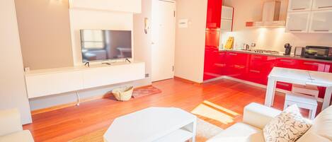 Un salon moderne avec un téléviseur à écran plat, un canapé blanc et une petite table blanche.
