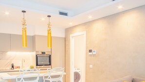 A modern kitchen with a central island, white bar stools, and pendant lighting.