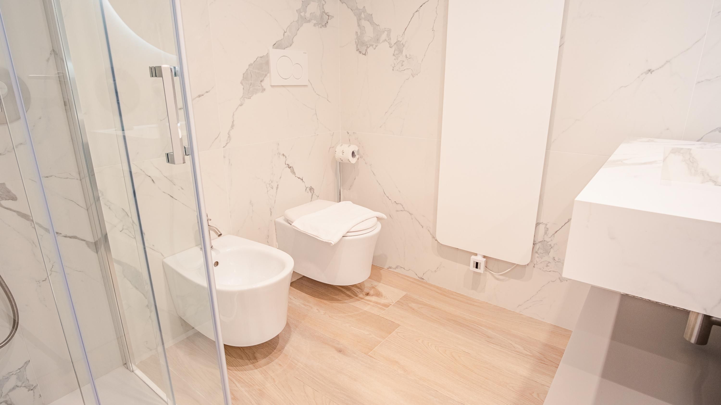 Un baño moderno con cabina de ducha de vidrio, un lavabo blanco y un inodoro.