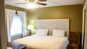A bedroom with a large bed, a ceiling fan, a nightstand, a lamp, and a chair. - Gulf-front condo on Okaloosa Island with balcony and views (Fort Walton Beach)