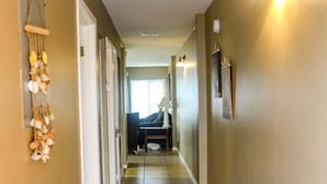 A hallway with beige walls, a black rug, and a ceiling light fixture. - Gulf-front condo on Okaloosa Island with balcony and views (Fort Walton Beach)