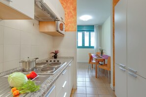 Una cucina con piano cottura, lavello e zona pranzo con tavolo e sedie.