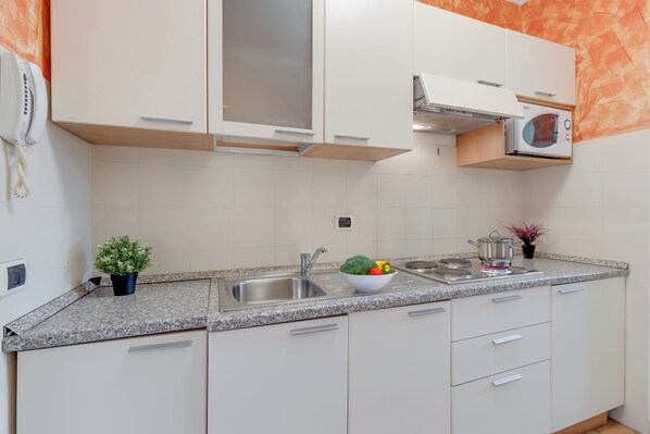 A modern kitchen with white cabinets, a granite countertop, a built-in microwave, and a sink. - Porto Letizia P20, Porlezza, Italy (Porlezza)