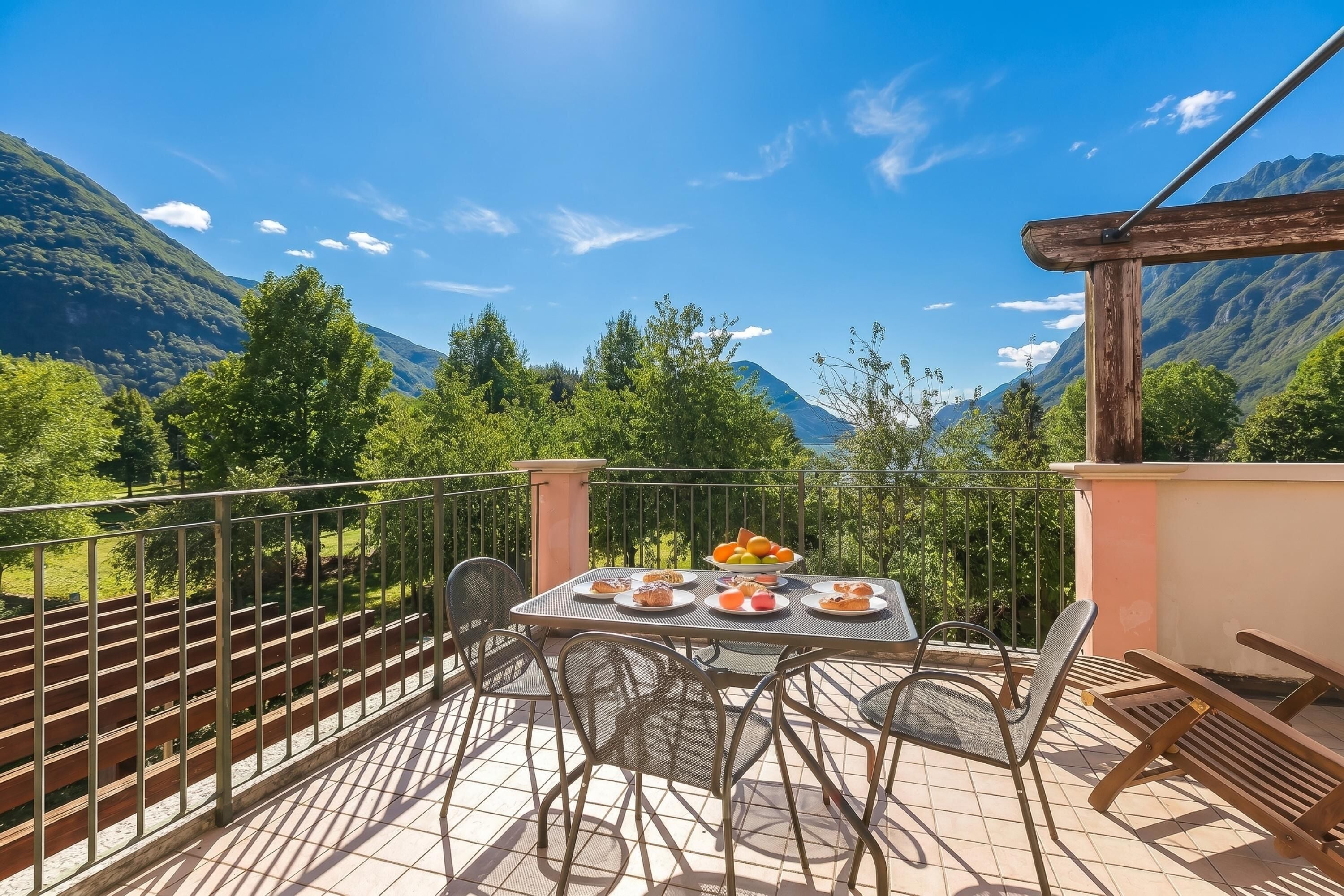 Een balkon met een eettafel, stoelen en uitzicht op bergen.