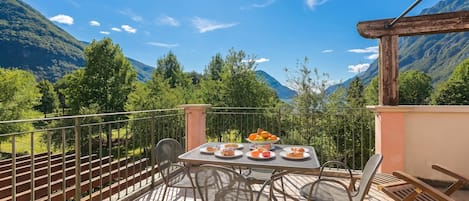 Een balkon met een eettafel, stoelen en uitzicht op bergen.