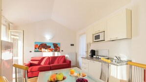 A modern kitchen with a microwave, sink, and a dining area with a table set for breakfast. - Porto Letizia Begonia 7, Porlezza, Italy (Porlezza)