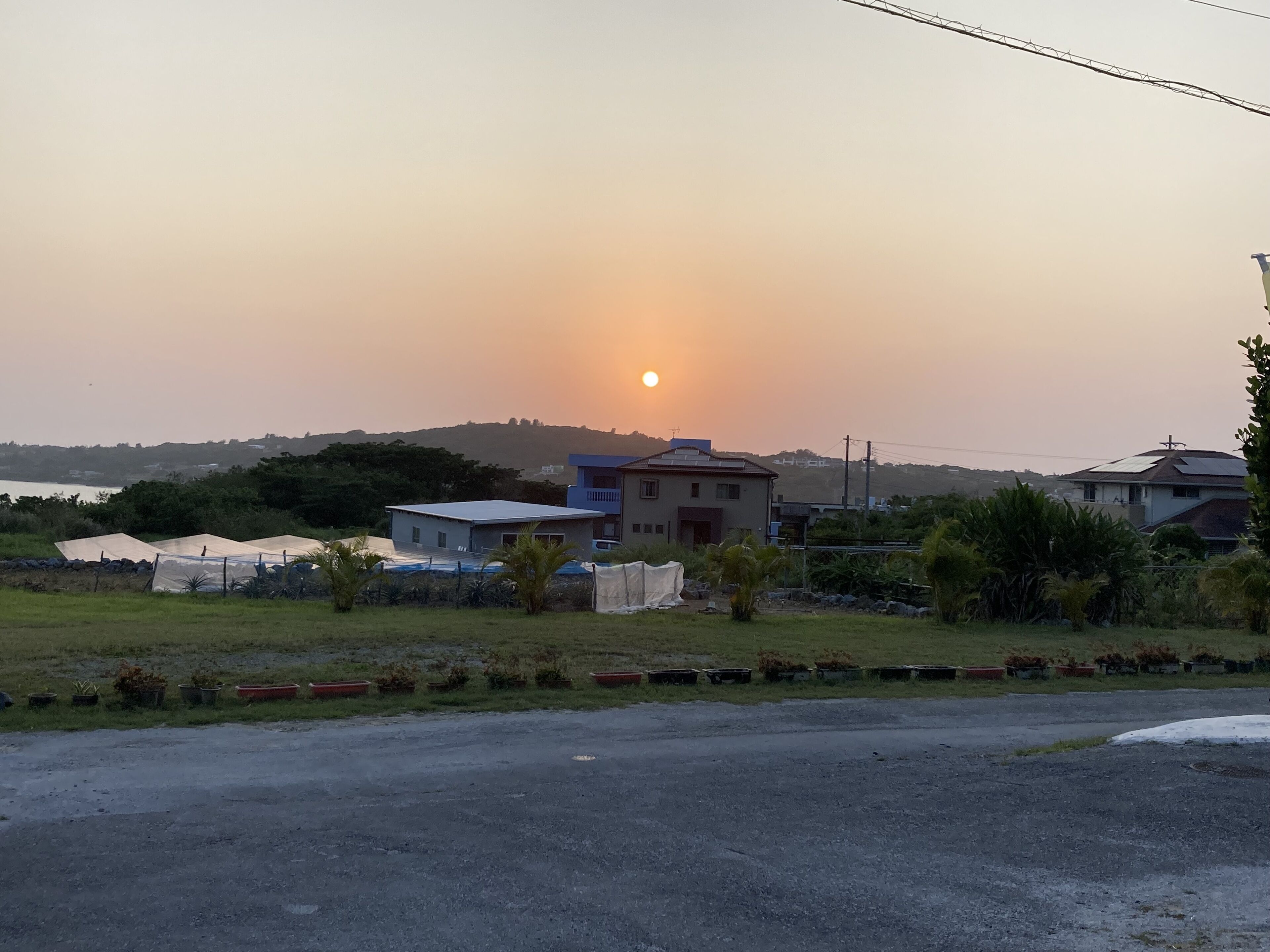 A residential area with houses, a paved road, and a body of water in the background.
