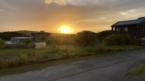 A residential area with houses, a road, and a sunset. - Pension Shimakaze (Motobu)
