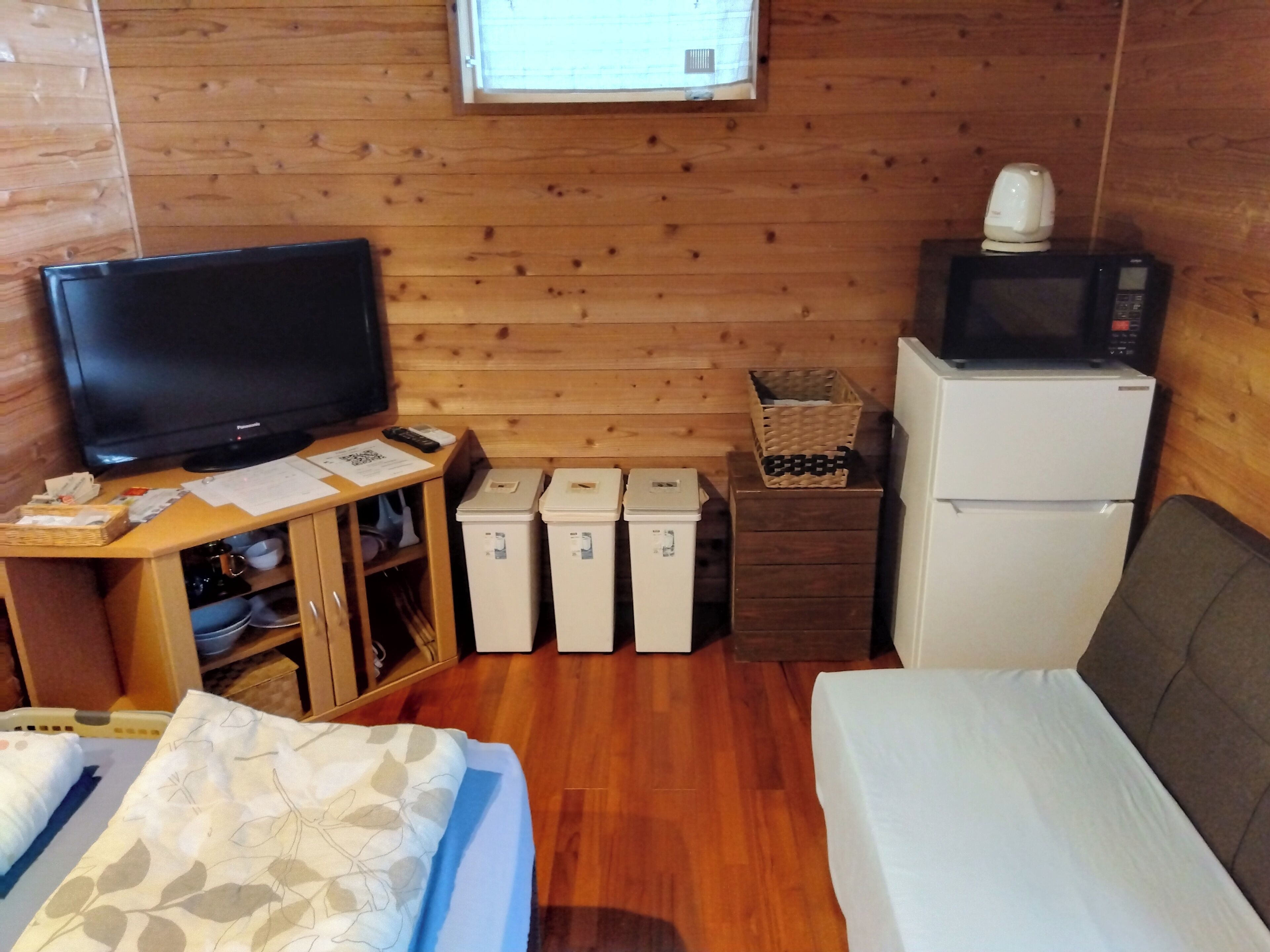 A wooden-paneled room with a television, a microwave, a refrigerator, and a bed.