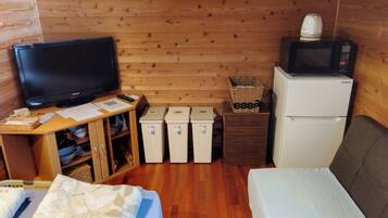 A wooden-paneled room with a television, a microwave, a refrigerator, and a bed.