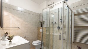 Un baño moderno con ducha de vidrio, lavamanos blanco y retrete.
