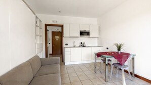 A compact living space with a kitchenette, a dining table with chairs, and a sofa. - Porto Letizia S1, Porlezza, Italy (Porlezza)