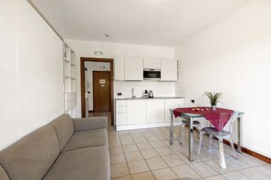 A compact living space with a kitchenette, a dining table with chairs, and a sofa.