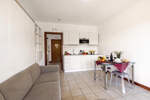 Um espaço compacto com cozinha compacta, área de jantar com mesa posta para dois e um sofá.