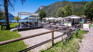 Un área de estar al aire libre con mesas y sillas, una zona cubierta para sentarse y bicicletas estacionadas cerca.