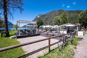 An outdoor seating area with tables and chairs, a covered seating area, and bicycles parked nearby.