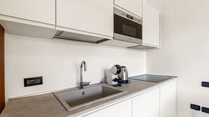 A modern kitchen with a stainless steel sink, a coffee maker, and a built-in oven. - Porto Letizia S1, Porlezza, Italy (Porlezza)