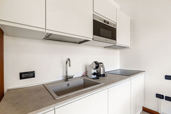 A modern kitchen with a stainless steel sink, a coffee maker, and a built-in oven.