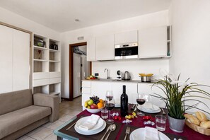 Cozinha moderna com armários brancos, forno embutido e área de refeições preparada para uma refeição.