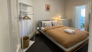 A bedroom with a bed, bedside table, lamp, and a wardrobe. - Cosy Flat metres from Rottnest Ferry (Fremantle)
