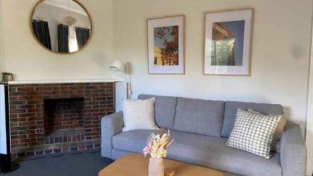 A living room with a grey sofa, a wooden coffee table, a fireplace, a round mirror, and two framed pictures on the wall. - Perfect Flat meters from WA Shipwrecks Museum (Fremantle)