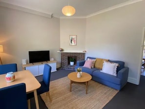 Una sala de estar con sofá, mesa de centro, televisor, chimenea y comedor con sillas y una mesa.