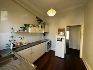 Una cocina con pileta, cocina, gabinetes, refrigerador y lámpara colgante.