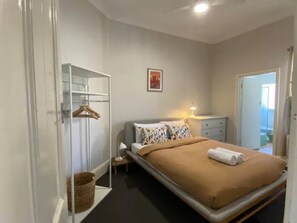 Un dormitorio con cama, mesita de noche, lámpara y armario.
