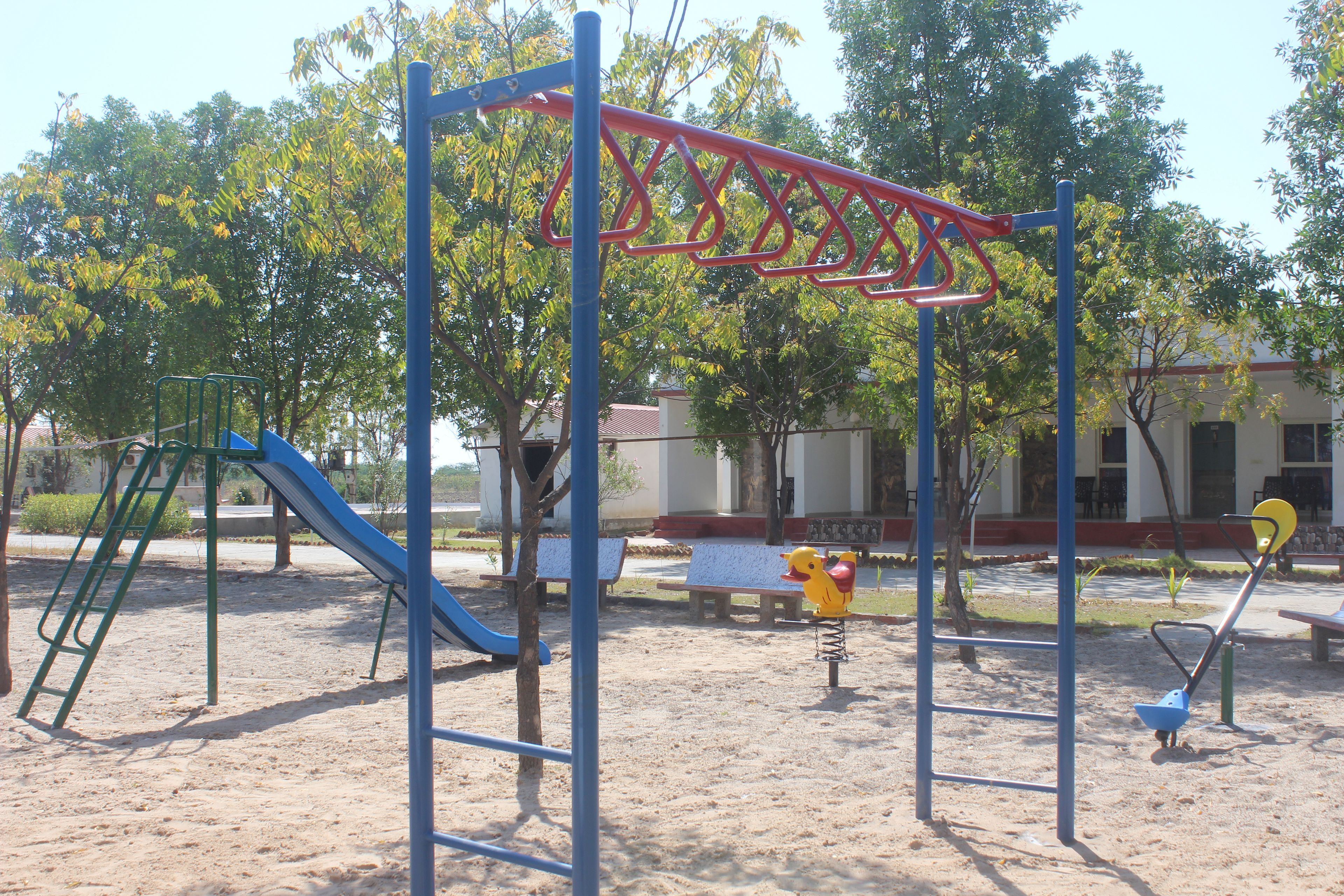 Uma área de recreação infantil com escorrega, balanços e estrutura de escalada.