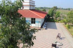 A building with a red roof and a paved patio area with two chairs.