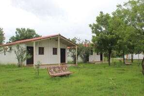 A white building with a red roof, a small garden, and a bench.